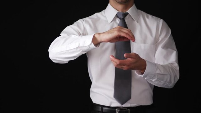 Professional businessman in a suit standing against a black background making a circular motion gesture with his hands showing one palm up and one down