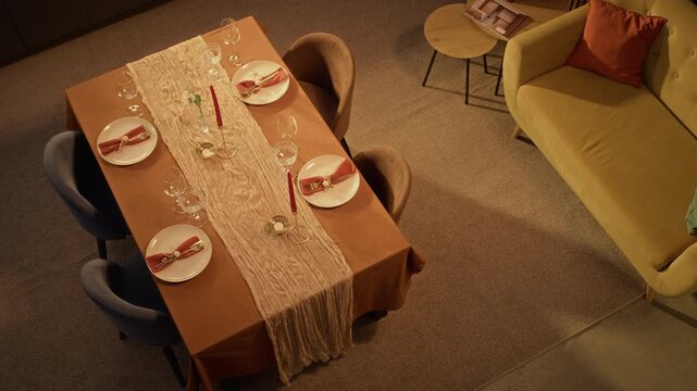 Festive dining table served with dinnerware, wine glasses and candles filmed from high angle. Footage ideal for Thanksgiving marketing and holiday party promotions