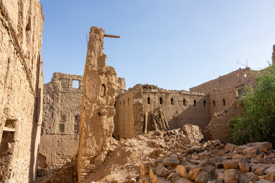 Rubble and collapsed walls of a ruined mudbrick village beneath a clear blue sky, Ad Dakhiliyah Region, Al Hamra, Oman