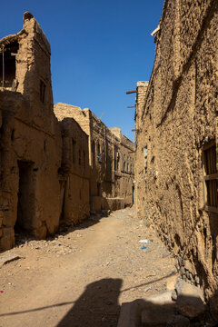 Narrow sunlit street running between rows of two-story mudbrick houses, Ad Dakhiliyah Region, Al Hamra, Oman