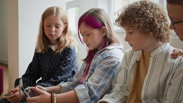 Caucasian schoolchildren sitting together, interacting and watching content on digital tablet. Suitable for modern education campaigns, e-learning platform advertisements, and EdTech video projects
