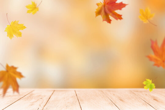 Empty wooden table with falling maple leaves for an autumn product display