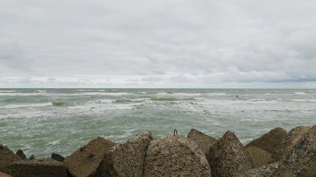 Concrete breakwater blocks on coastline with stormy sea waves