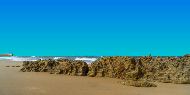 Rocky beach with breaking waves and clear blue sky