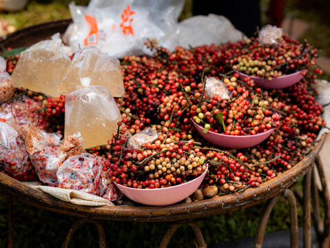 Fresh ripe mak mao berries or Antidesma bunius displayed in bowls on woven tray at market