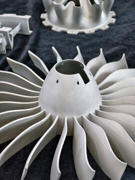 Metal turbine parts displayed on a dark surface showing intricate design
