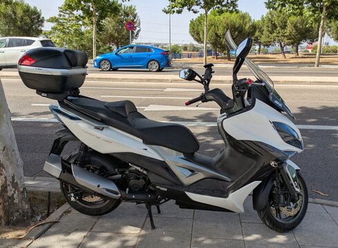 Vista lateral de moto scooter Kymco Xciting 400i con ba&uacute;l trasero GIVI V46 Monokey System, estacionada en Madrid, Espa&ntilde;a, 21 de junio de 2026