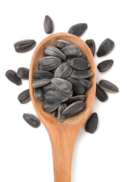 Sunflower seeds in a wooden spoon and scattered on a white background. Top view