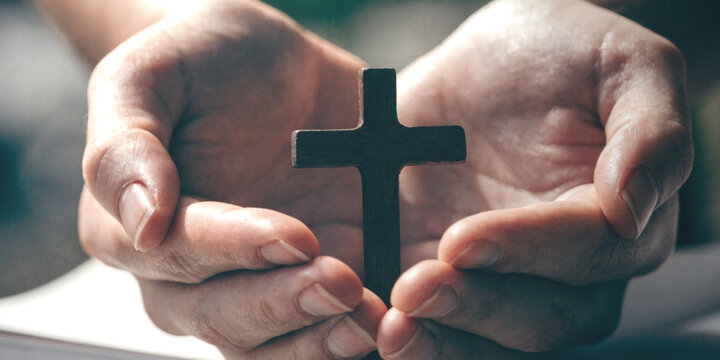 Lifestyle believe. Praying and faith with spiritual hope with hands clasped holding a small Christian cross
