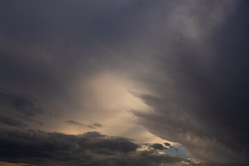 Obraz premium Moody Stormy Sky with Soft Light Breaking Through Dark Clouds. Moody evening sky dominated by extensive dark storm clouds, with a soft opening of pale light appearing above the distant horizon. 