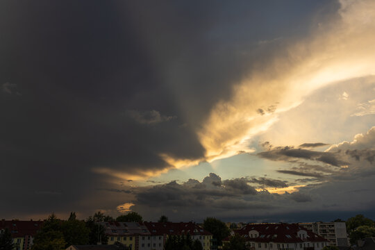 Dramatic Sunset Sky with Storm Clouds Above a Distant Horizon. A dramatic sunset landscape featuring a dark storm front on one side and brilliant golden light illuminating the clouds on the other. 