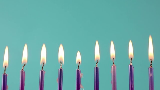 Nine metallic pink and purple birthday candles burning in a row against a dark blue background, isolated. Happy Birthday card design concept.  Bottom lower border edge a lot of copy space. 
