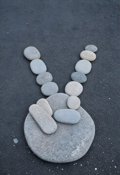 Peace sign gesture made of smooth river stones harmony and unity concept zen balance and mindfulness creative rock art on dark asphalt background
