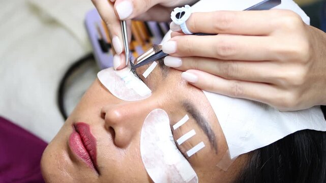 The process of eyelash extension and volume increase in a professional beauty salon, close-up view