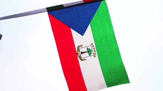 Equatorial Guinea national flag waving in the wind, representing Independence Day, national pride and national identity. Green, white and red flag with blue triangle and national coat of arms, suitabl