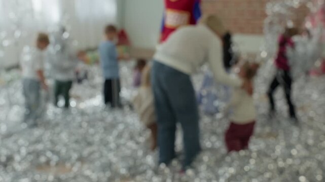 Blurred children celebrating in bright party room with confetti, colorful costumes, and playful movement