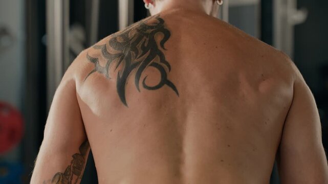 Caucasian young adult man exercising on gym cable machine, pulling weight and engaging back muscles. Visual works well for bodybuilding commercials and fitness club promotions