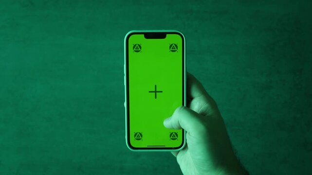 Hand holding phone with chroma key green screen, mockup mobile phone at modern office closeup, businesswoman reading work message on green screen smartphone at workplace. 
