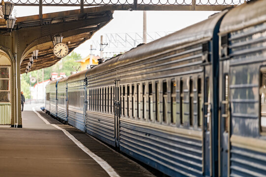 passenger train standing at the railway station platform with classic clock.