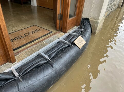 temporary flood barrier at a generic home entrance Flood barrier blocking water from entering a building entrance during flooding.