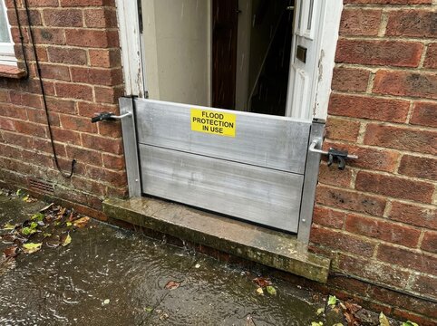 temporary flood barrier at a generic home entrance Flood barrier protecting a door on a brick building during heavy rain.