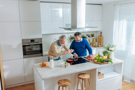Senior men cooking breakfast together in kitchen