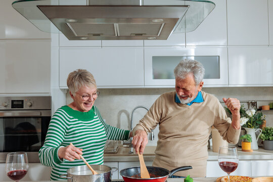 Senior couple cooking and dancing in kitchen