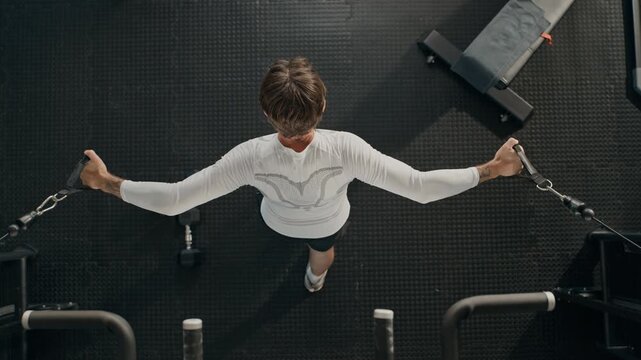 Young adult Caucasian man performing cable crossover chest exercise in gym, top view. Visuals perfect for fitness app promotions, bodybuilding marketing and athletic campaigns