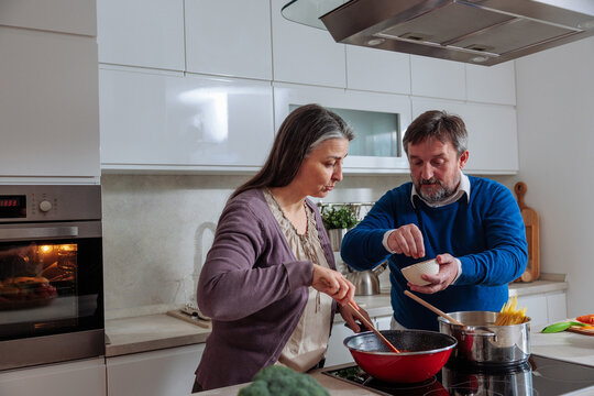 Senior couple cooking dinner together in modern kitchen