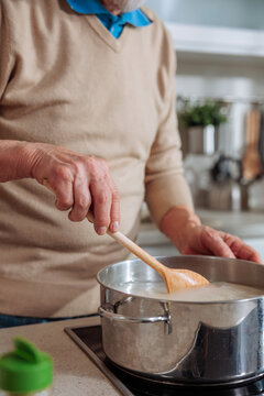 Senior man stirring food in cooking pot on stove