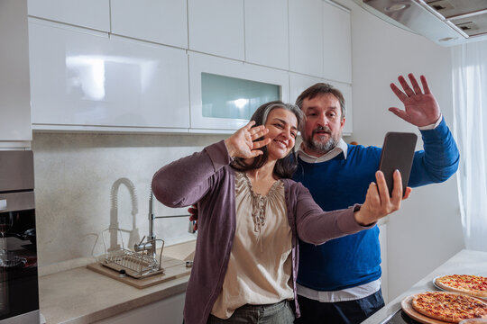 Senior couple video calling with smartphone in kitchen