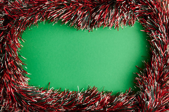 Christmas tinsel garland frame on green background with copy space