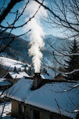 Obraz premium Snow covered village houses with smoke rising from chimney. Winter scene in mountains. Cold weather and heating inside residential buildings. Rural home warmth.