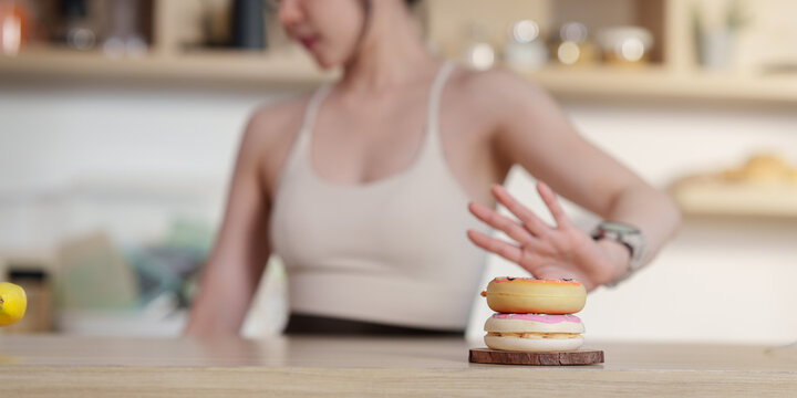 Woman making stop hand gesture to reject donuts for healthy eating choice