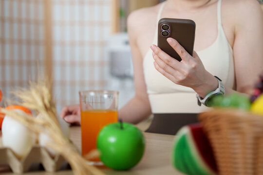 Asian woman holding smartphone near healthy breakfast and fresh juice for nutrition concept