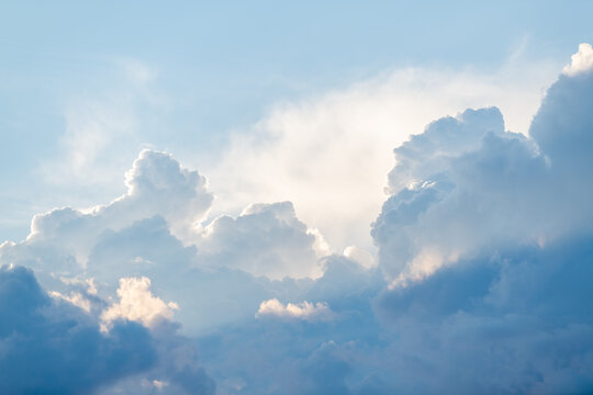 Fluffy white cumulus clouds glowing with soft sunlight against a blue sky.