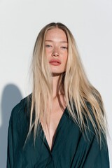 Fototapeta premium Natural light portrait of a freckled blonde woman with long hair wearing a deep green blouse for beauty portrait background and fashion banner