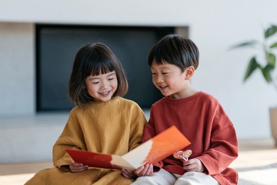 Smiling siblings reading a storybook together by a cozy modern fireplace for family lifestyle background and children's book banner design