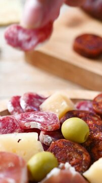 Hand taking sliced fuet from charcuterie board