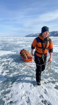 Brave explorer dragging a heavy equipment sled across a vast frozen expanse of a glacial lake during an extreme winter wilderness expedition