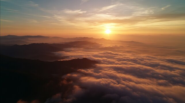 Vibrant golden sunrise illuminating vast mountain peaks rising above a thick carpet of soft white clouds in early morning light