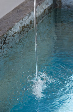 string of water pouring from small fountain pipe