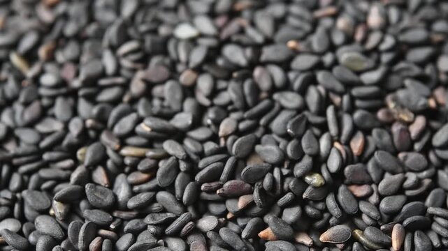 Macro view of black sesame seeds rotating slowly in bowl, revealing rich texture under soft light