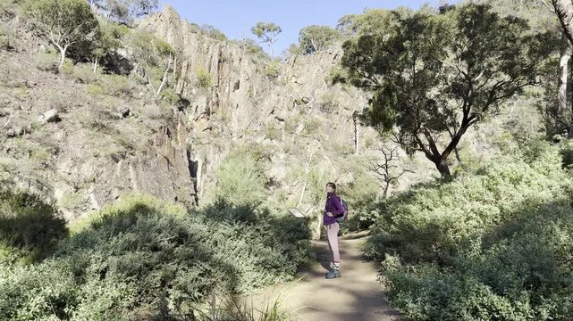 A girl hiker walks and admires the landscape, embracing the adventurous life in Australia, along the Werribee Gorge Circuit Walk, near Melbourne, Victoria, Australia.