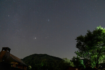 Pleiades cluster Taurus constellation and bright Jupiter over dark hill. © badescu