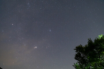 Pleiades cluster Taurus constellation and bright Jupiter over dark hill. © badescu