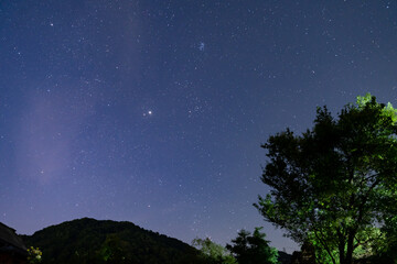 Pleiades cluster Taurus constellation and bright Jupiter over dark hill. © badescu