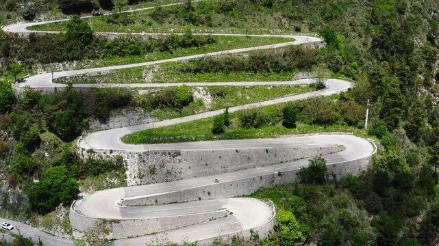 Aerial drone view of cyclist riding on winding mountain road near &Egrave;ze, French Riviera, France