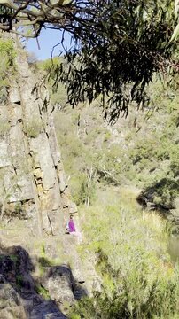 A girl sits on the slope of the powerful canyon, along the Werribee Gorge Circuit Walk, Werribee Gorge State Park, near Melbourne, Victoria, Australia.