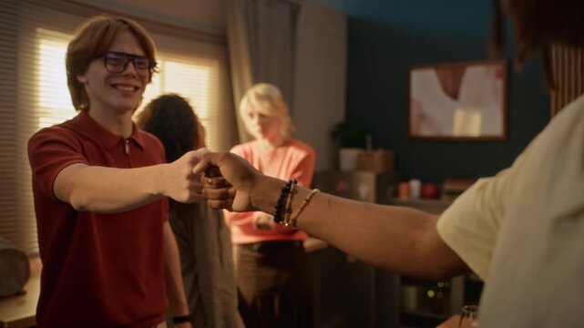 Caucasian young man doing fist bump with African American friend during multiethnic home gathering. Footage suited for friendship, holiday celebration, and social inclusion campaigns